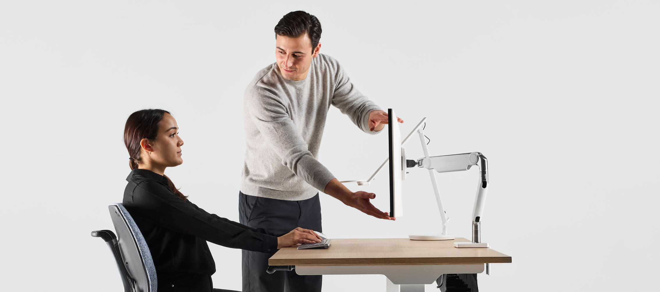 woman receiving ergonomic advice for setting up her monitor arm height